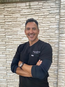 Dr. Lucero's headshot for staff page taken outside with a white wall background